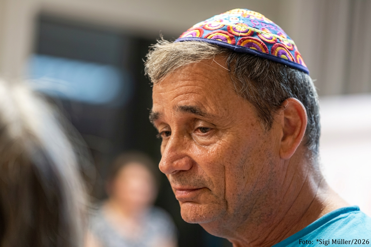 Ein Mann mit einem bunten Kippa, der nachdenklich schaut, Hintergrund unscharf.