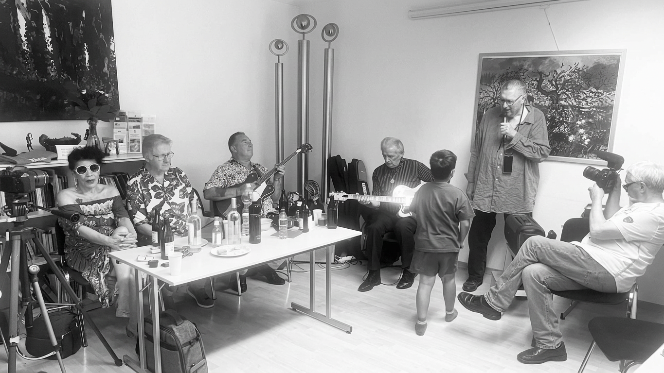 Eine Gruppe von Musikern und Zuschauern in einem Raum, wobei ein Junge auf eine Performance wartet, während andere mit Musikinstrumenten und Kameras beschäftigt sind.