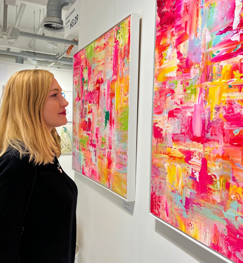 Eine Person betrachtet lebendige, abstrakte Gemälde in einer Kunstgalerie.